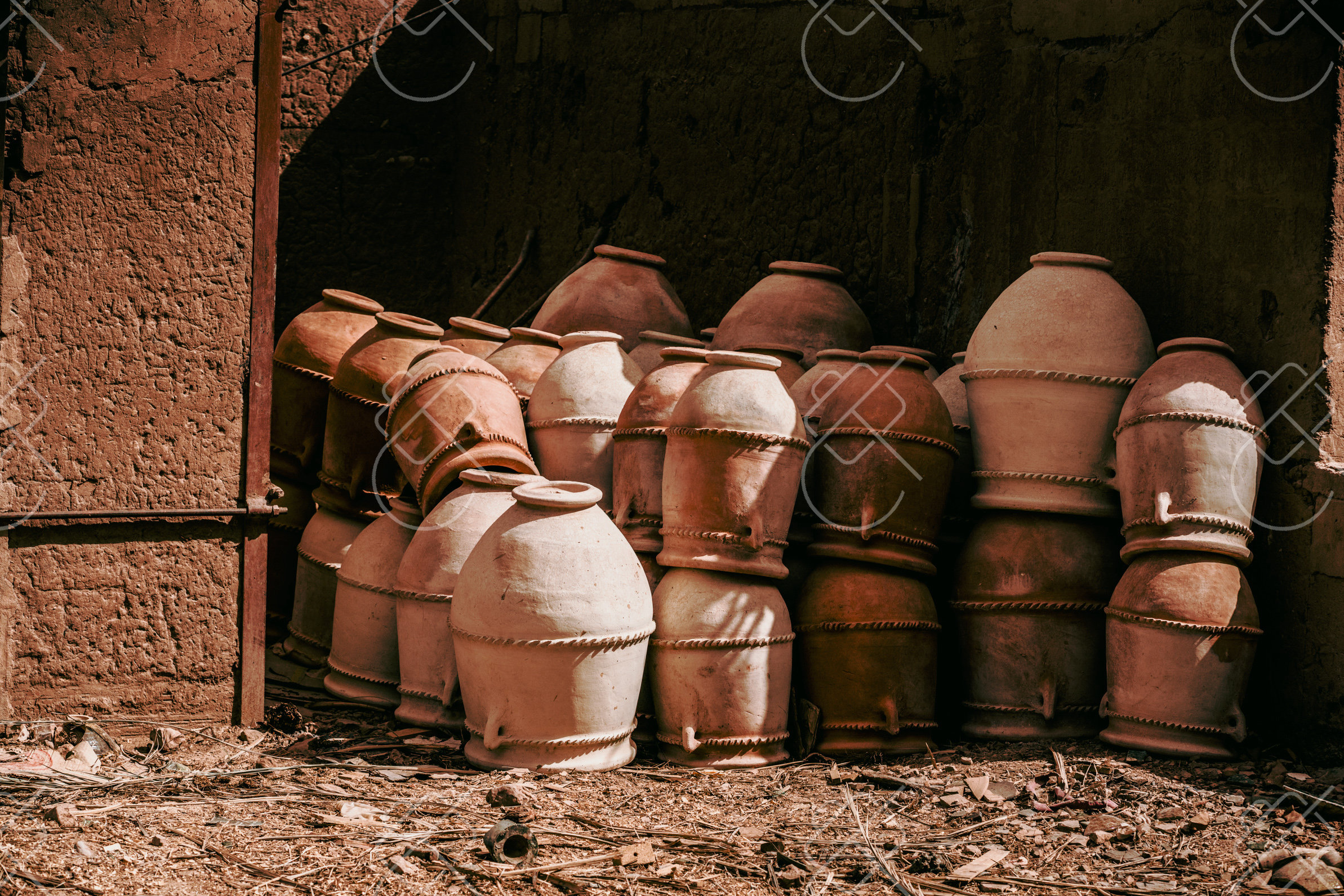 Large clay urns stacked and drying against a mudbrick wall — Tamgroute, fine art travel photography print available from Clever Tourists