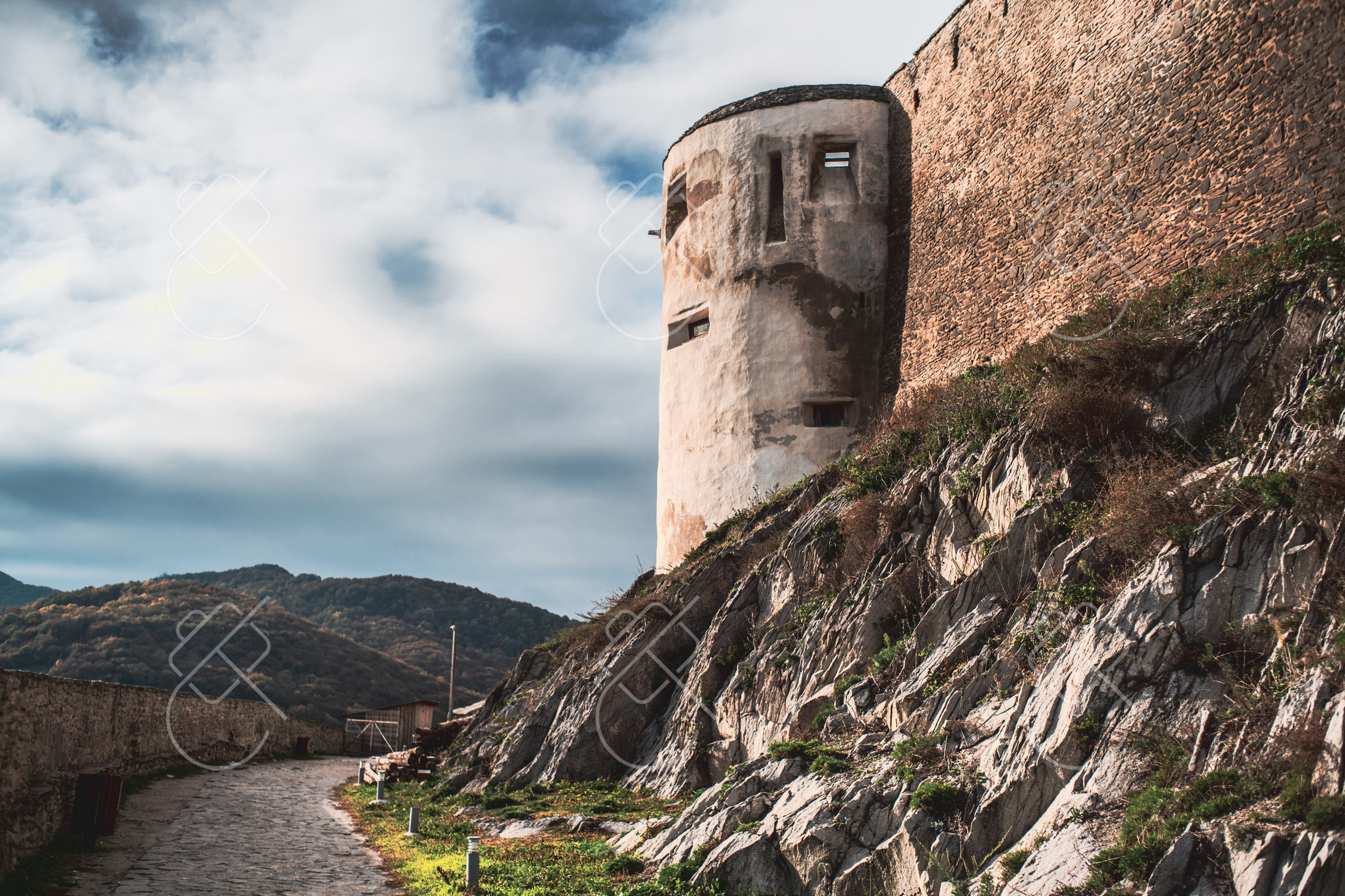 A stone tower of the Deva fortress rising above the road that climbs the hill — Deva
