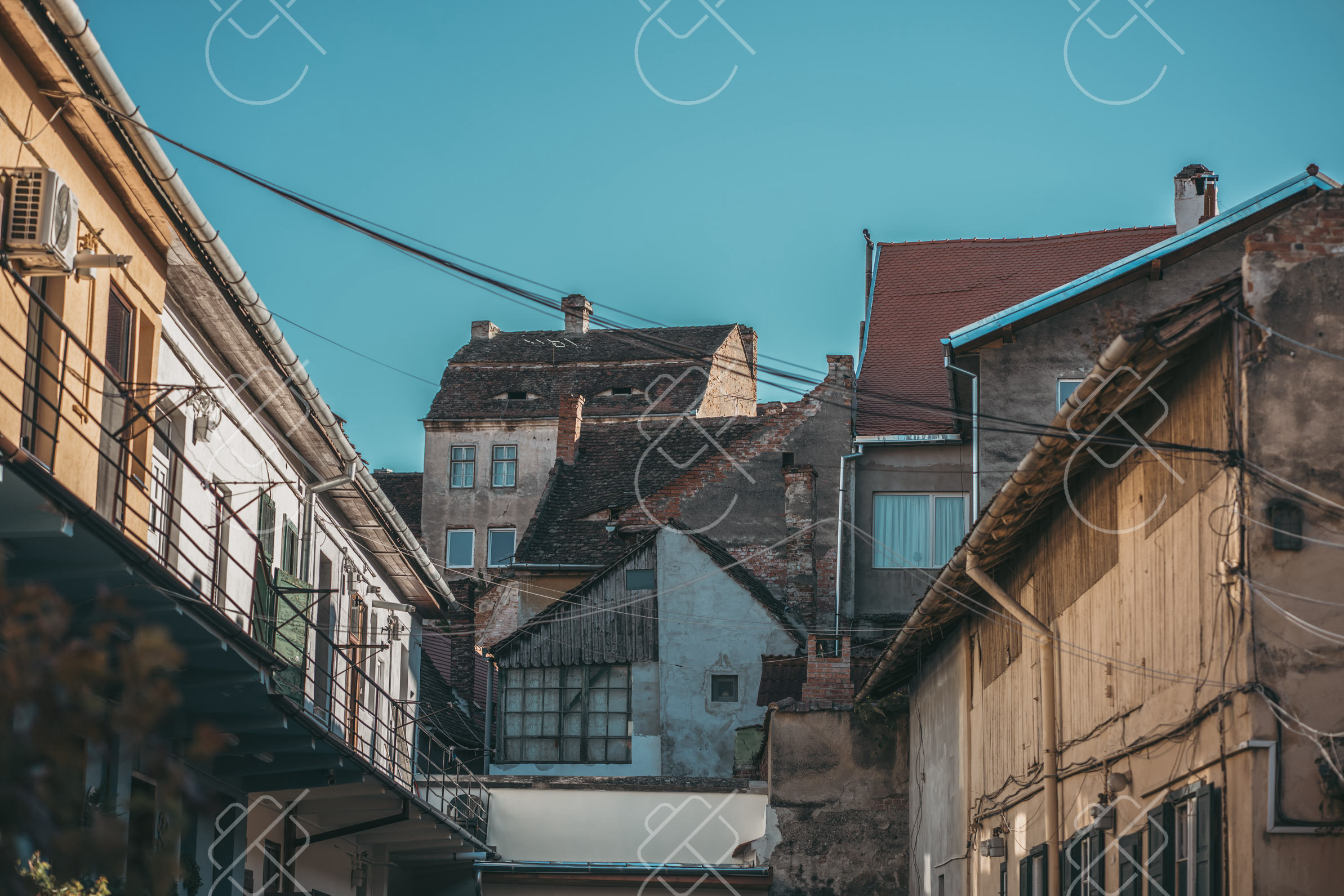 A quiet cobblestone alley winding between pastel Saxon townhouses in the old town — Sibiu, fine art travel photography print available from Clever Tourists