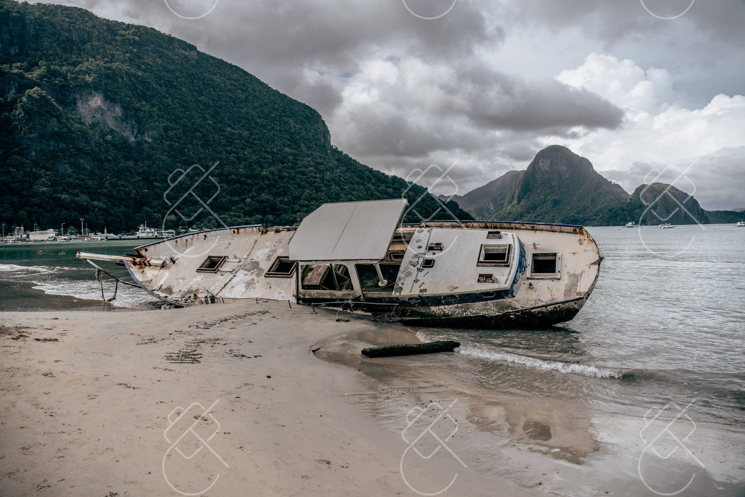 A weathered shipwreck rusting on the sand beneath El Nido's cliffs — El Nido, fine art travel photography print available from Clever Tourists