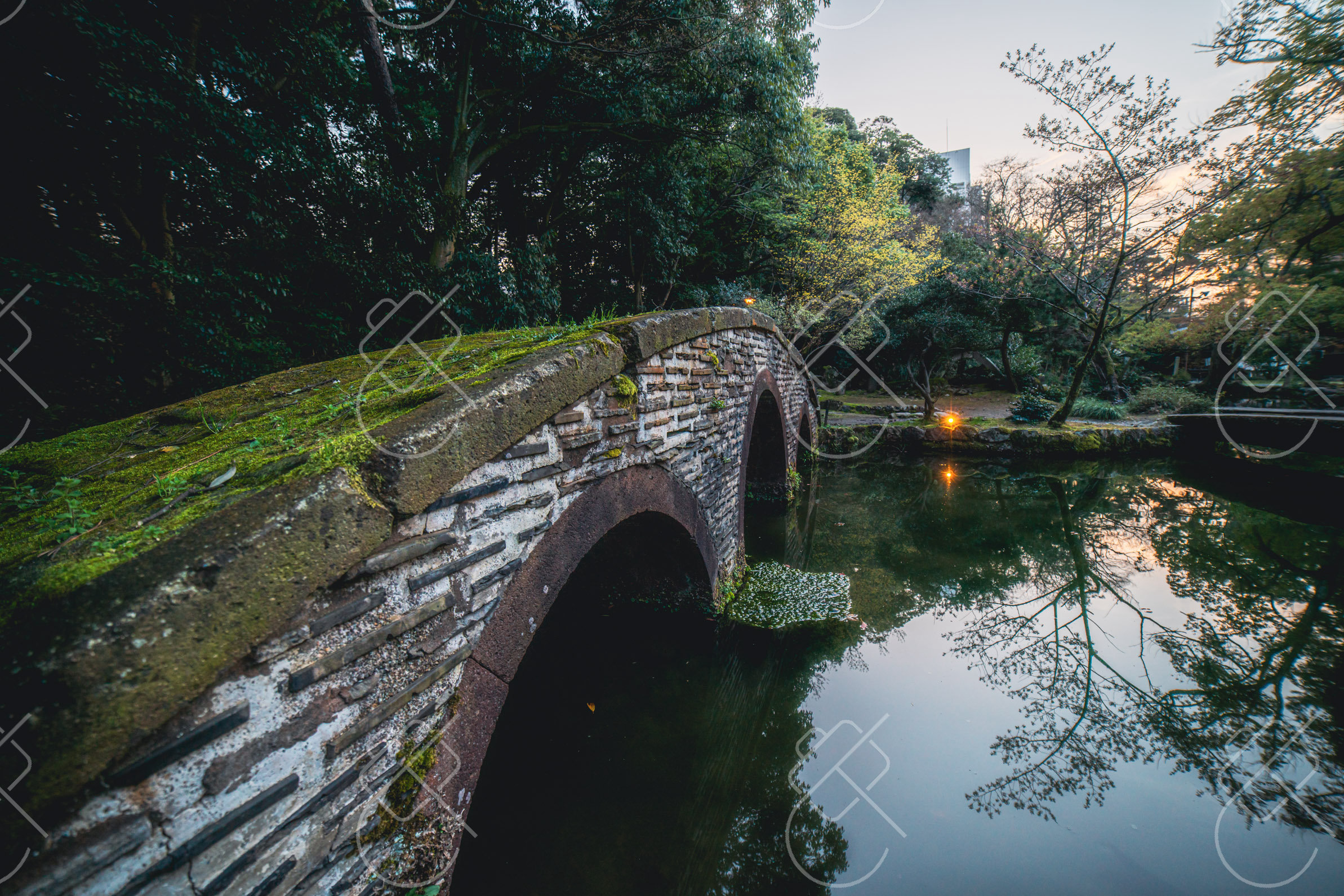 Stone arch bridge and moss-covered stepping stones crossing the pond in Gyokusen-inmaru Garden — Kanazawa, fine art travel photography print available from Clever Tourists