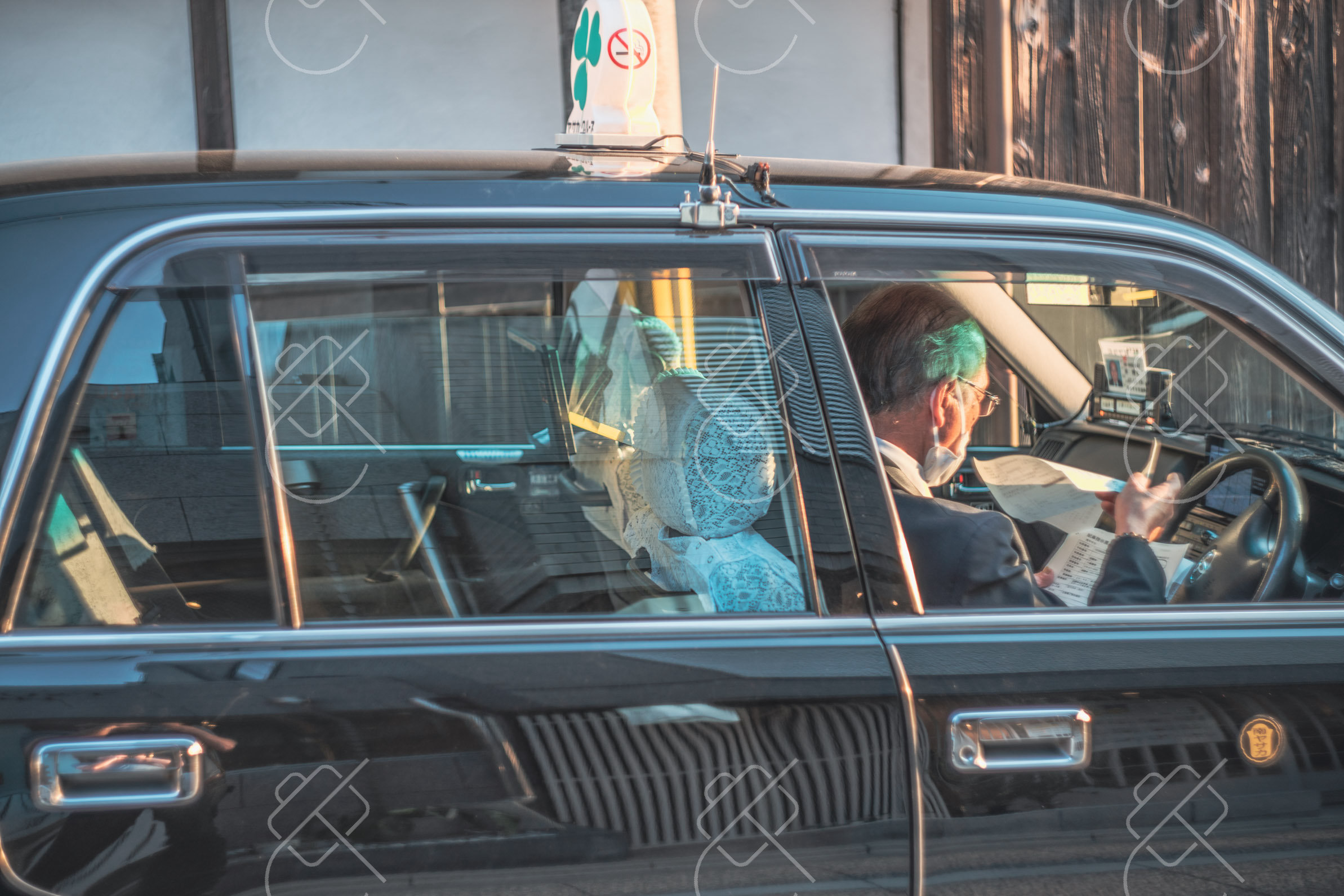 A Kyoto cab driver behind the wheel, white lace seat covers and all, a detail you'll see in taxis across Japan