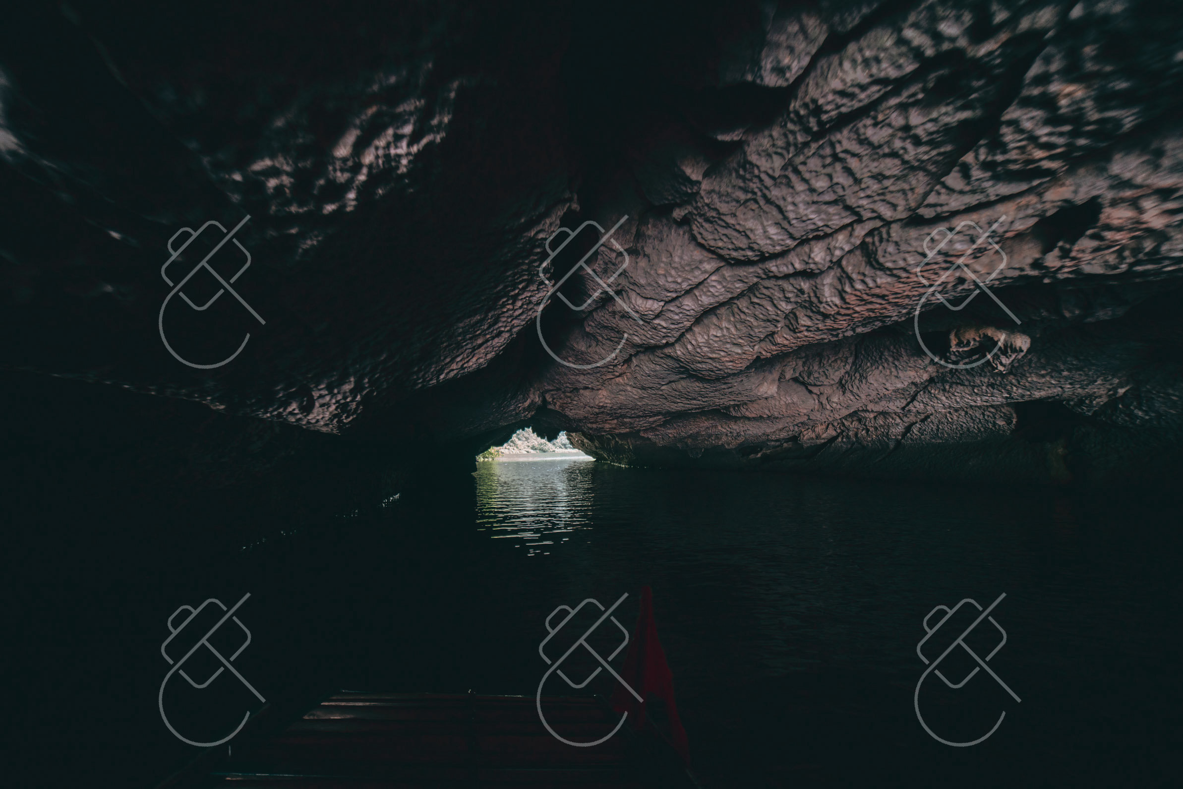 A small boat entering one of Trang An's low limestone cave passages — Trang An & Hoa Lu