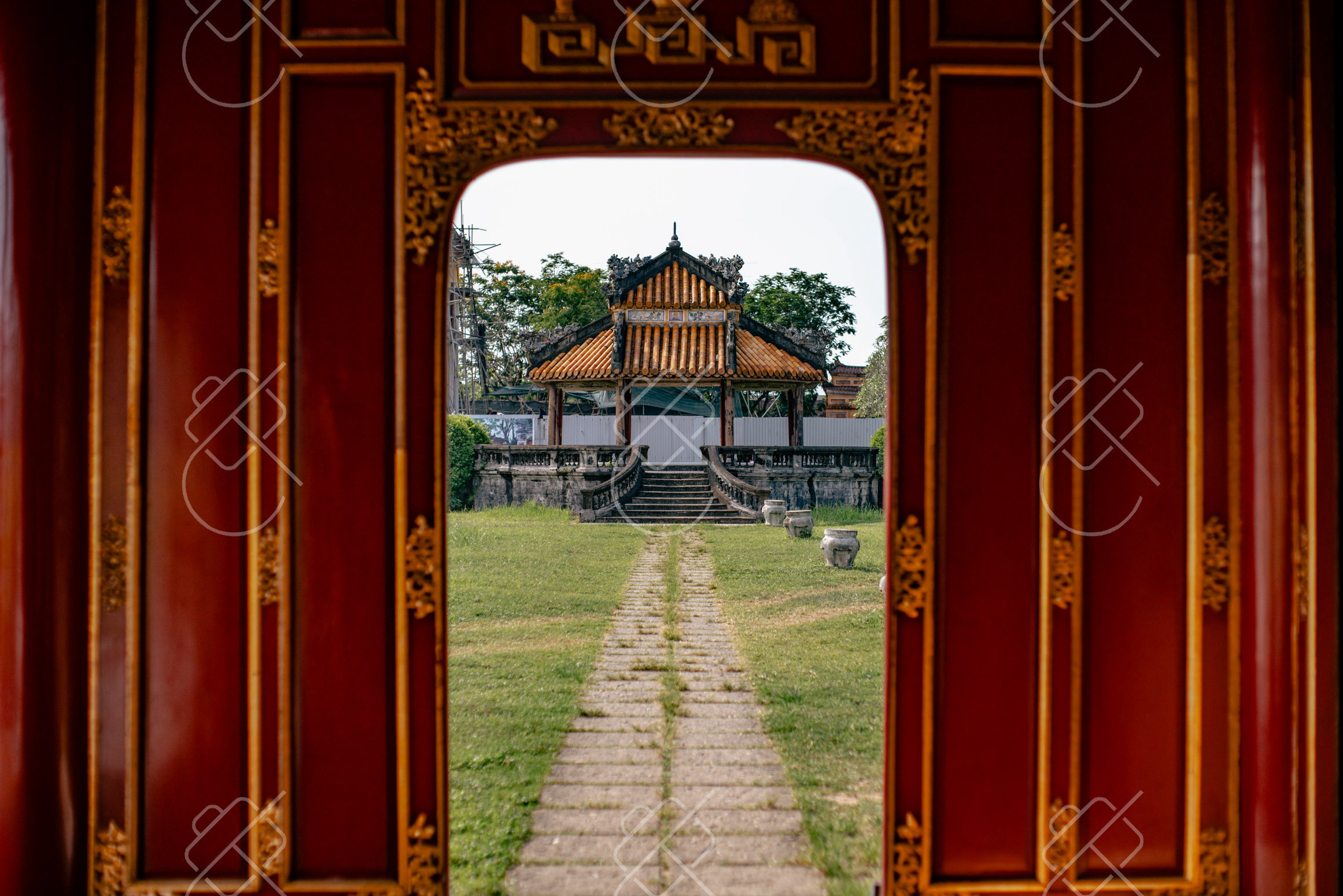 A red-and-gold palace doorway framing a pavilion across the Imperial City lawns — Hue, fine art travel photography print available from Clever Tourists