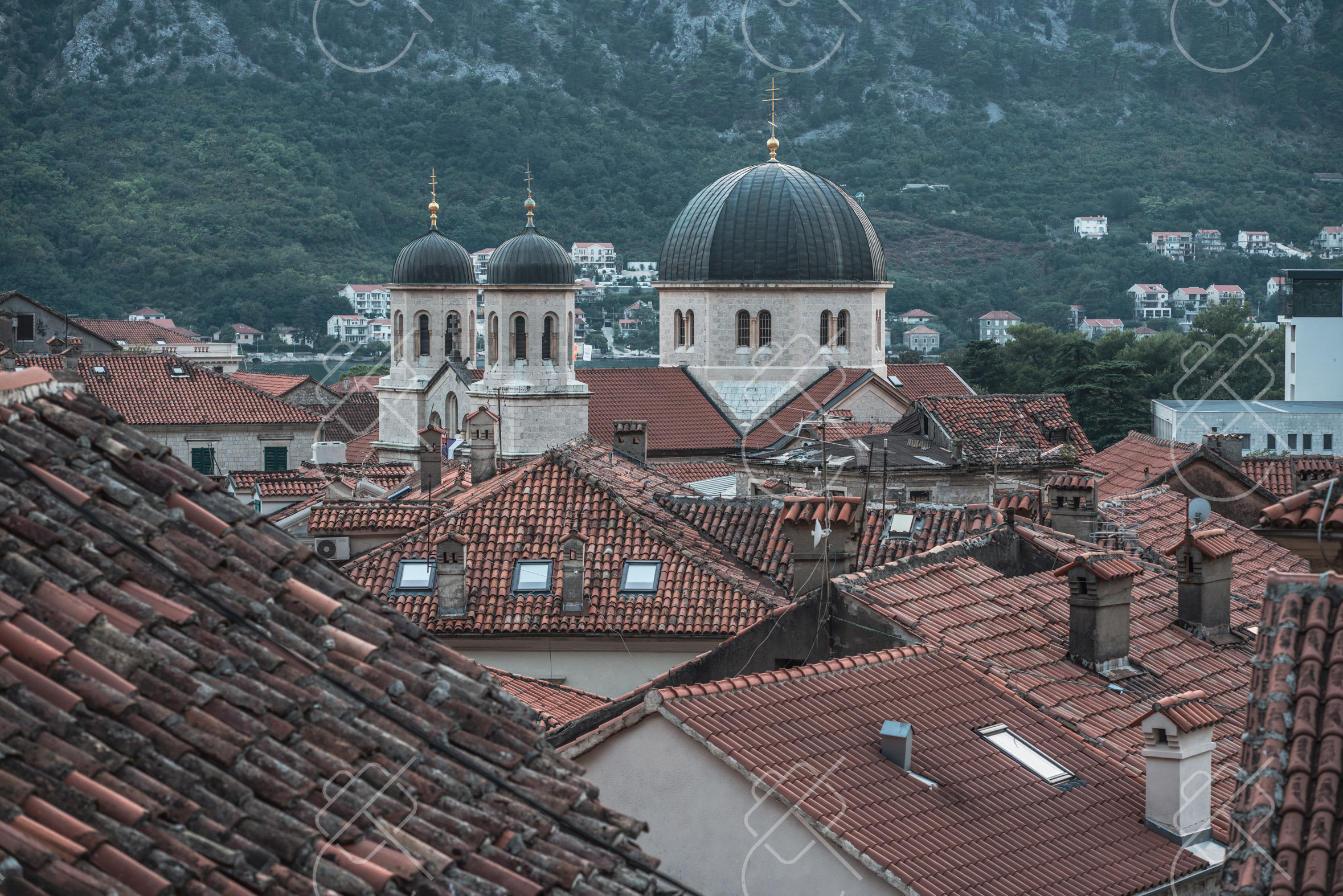 Terracotta rooftops and Orthodox church domes below the looming karst cliffs — Kotor, fine art travel photography print available from Clever Tourists