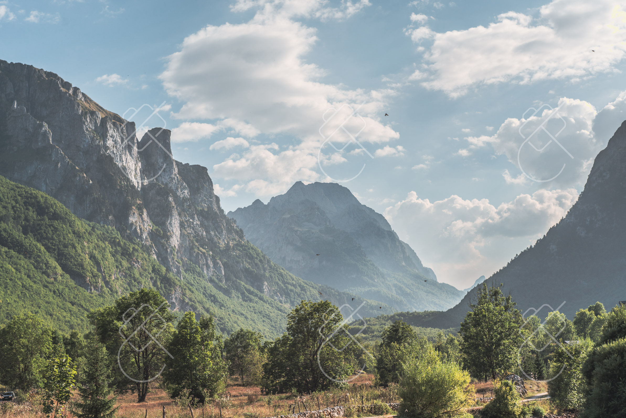 A hiking trail crossing open alpine grassland below the ridge — Gusinje