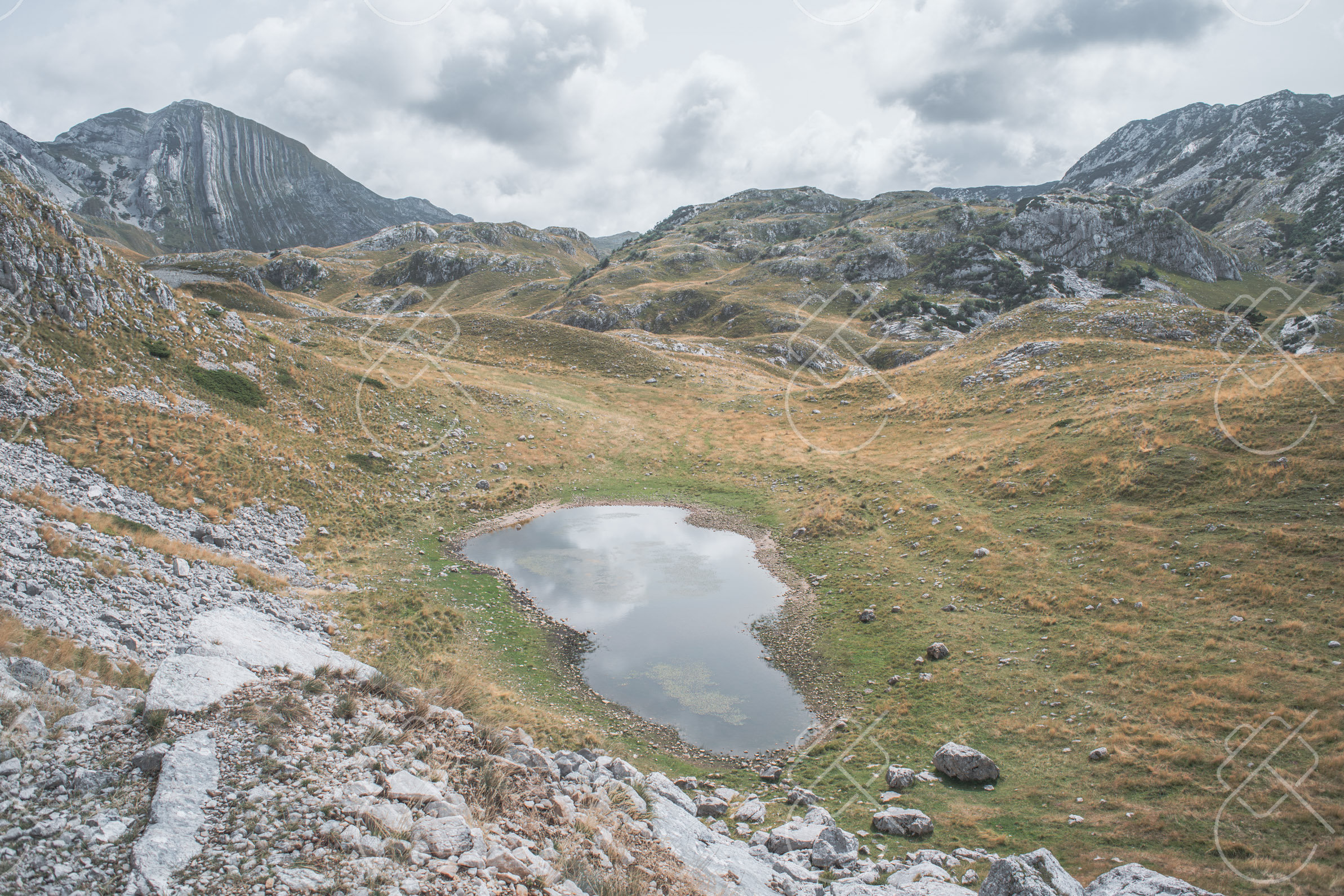 A shallow glacial tarn on the high plateau below the pass — Nikšić to Piva and the Durmitor Ring, fine art travel photography print available from Clever Tourists