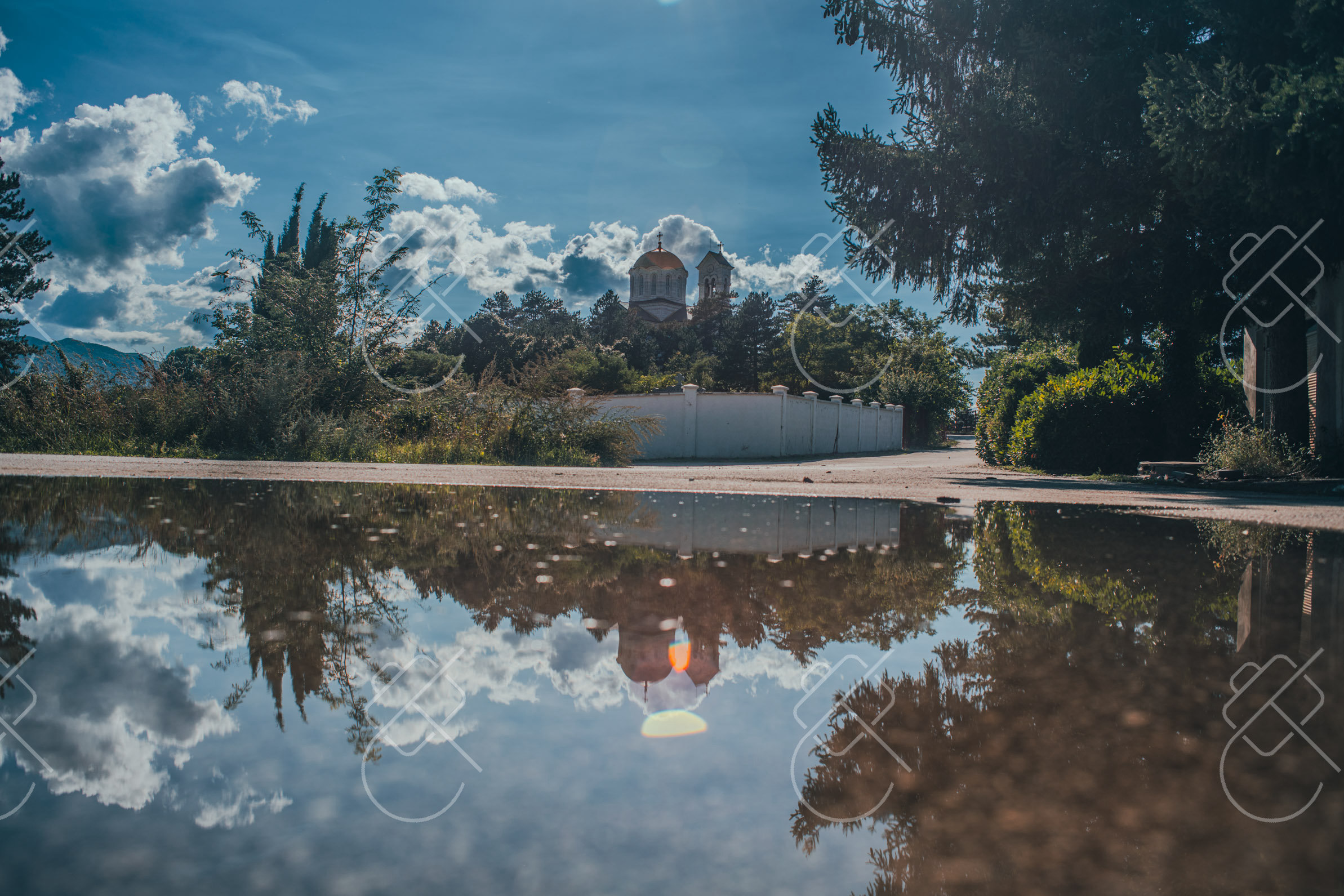 The cathedral on Petrova Glavica mirrored in rainwater on the road below — Central Nikšić, fine art travel photography print available from Clever Tourists